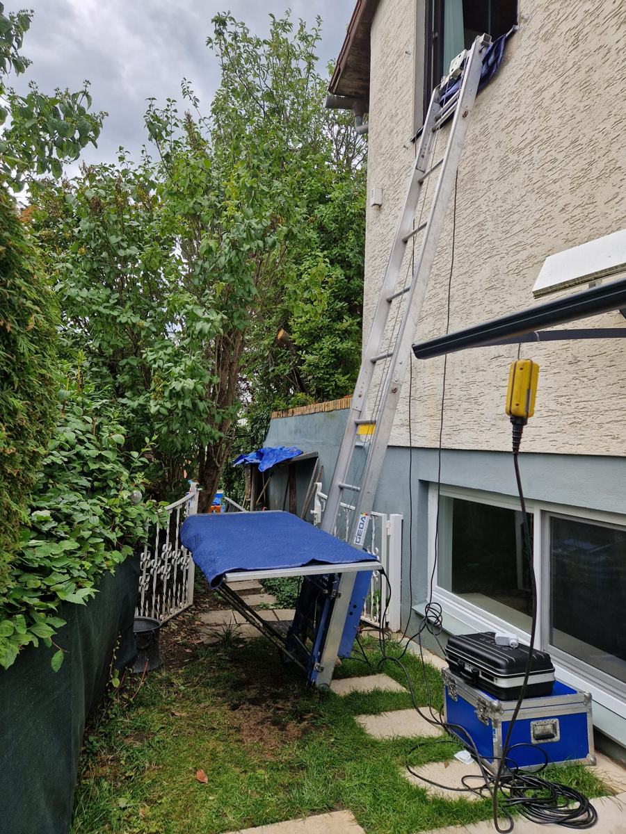 GEDA platform lift in a narrow garden path at a window